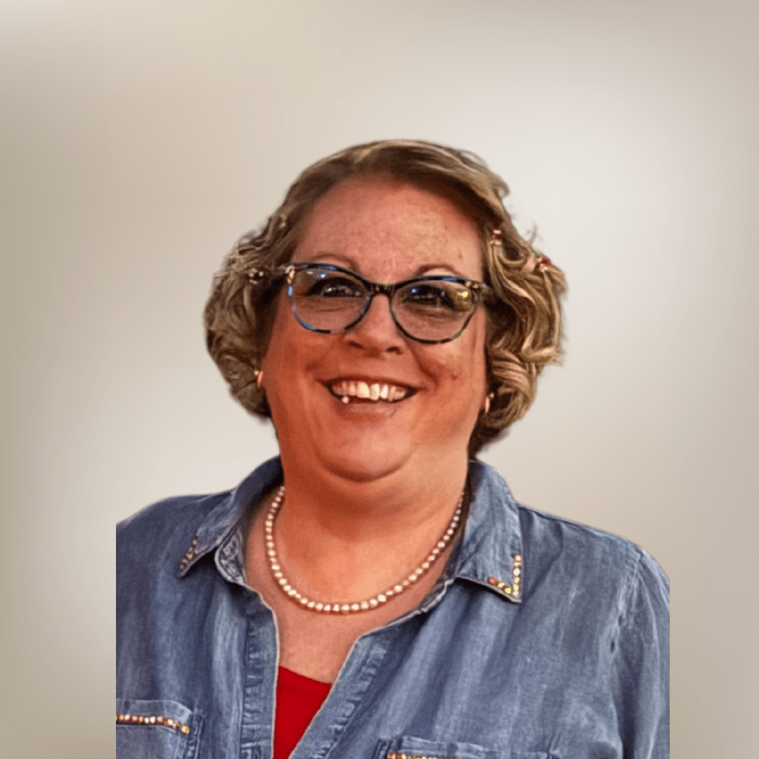 Smiling person with glasses wearing denim shirt