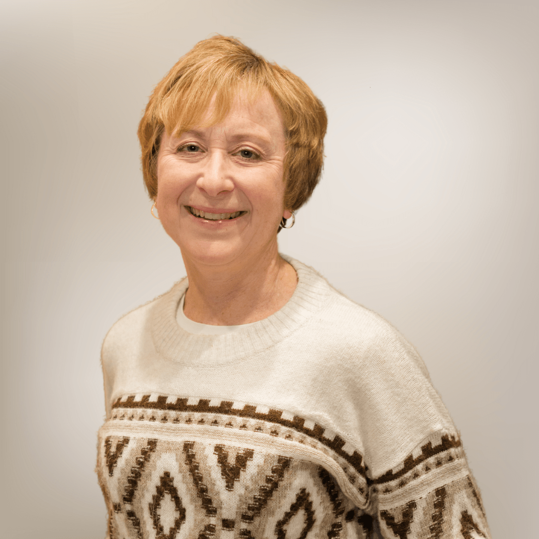 Smiling person in patterned sweater, gray background.