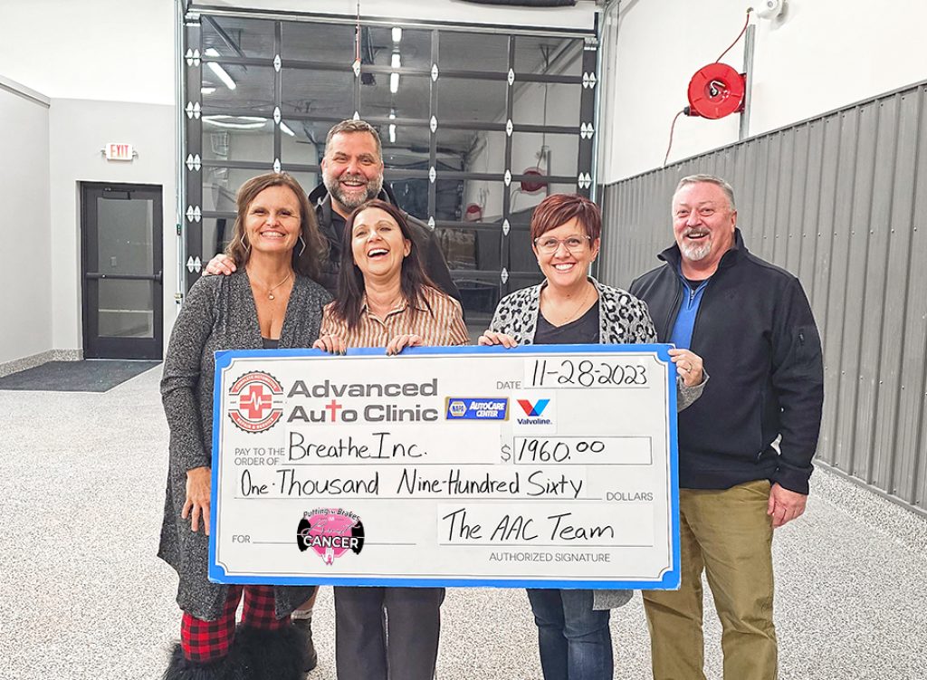Group holding charity donation check in garage